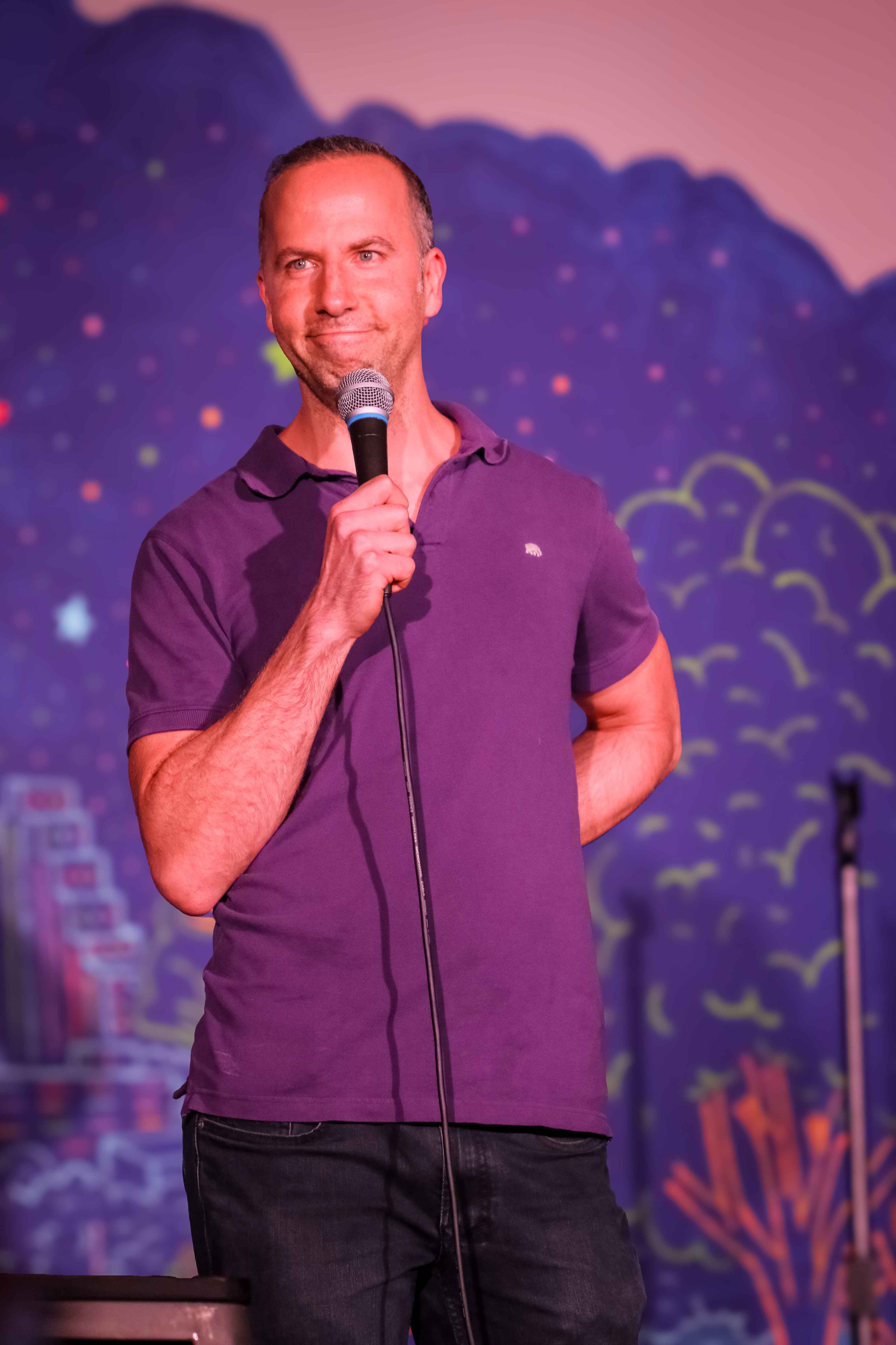 Hal Sadi performing stand-up comedy in a denim jacket